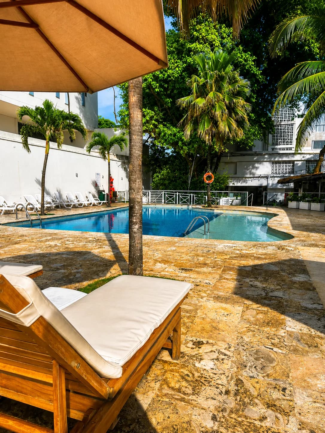 Tumbona junto a la piscina del Hotel Playa Club entre vegetación tropical